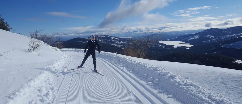 Photo of guy cross country skiing with mountain peak in background.