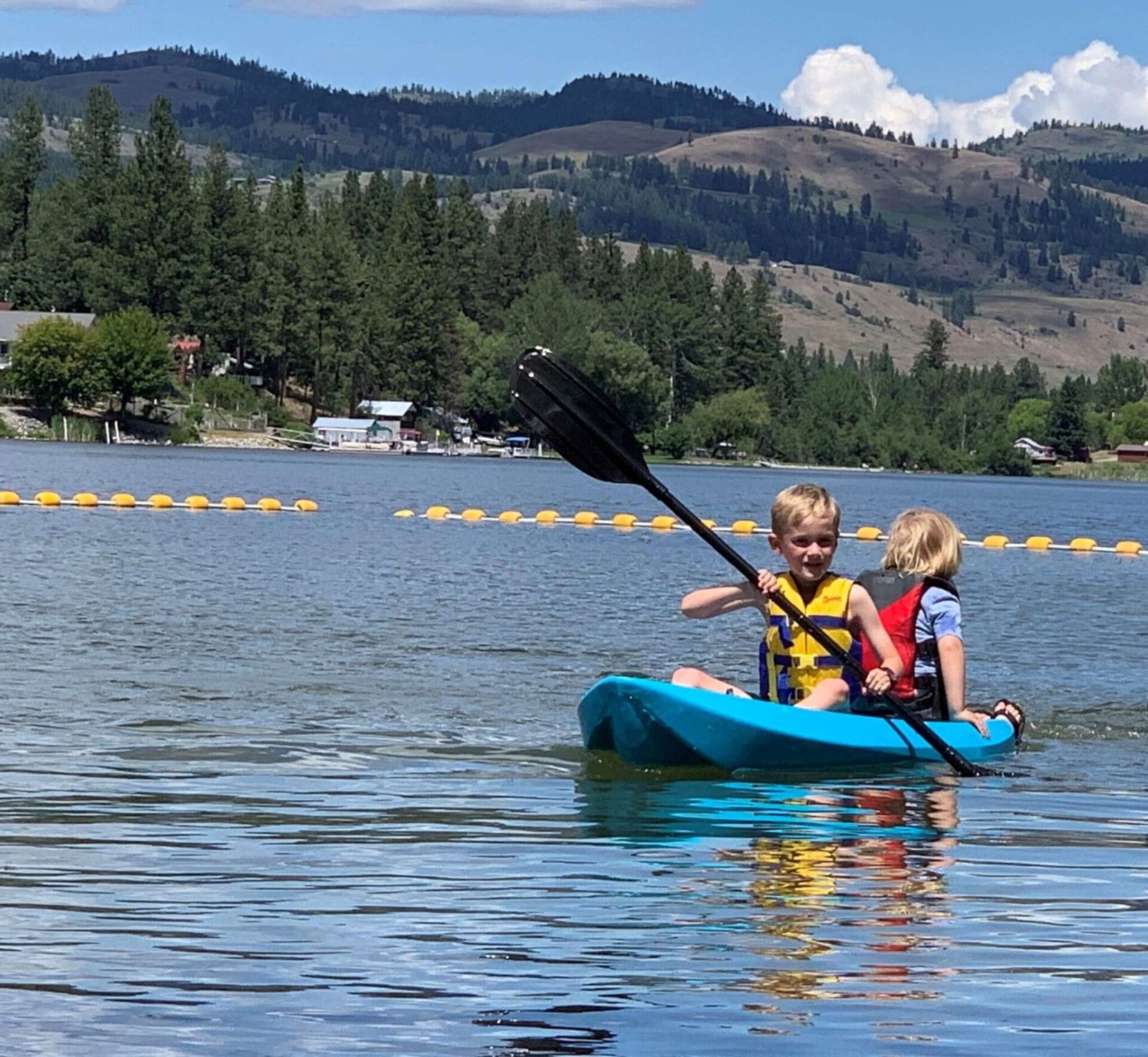 Two kids paddling on a lake.