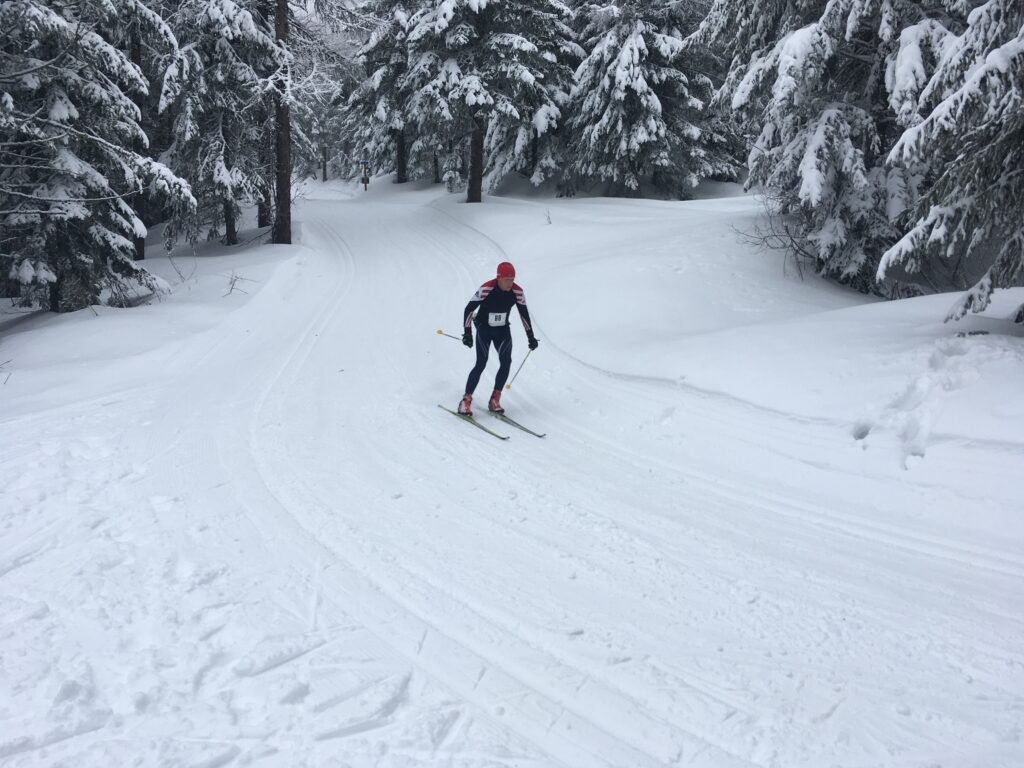 Spokane Nordic Ski Association member cross-country skiing down a slight hill and around a turn on a trail at Mount Spokane.