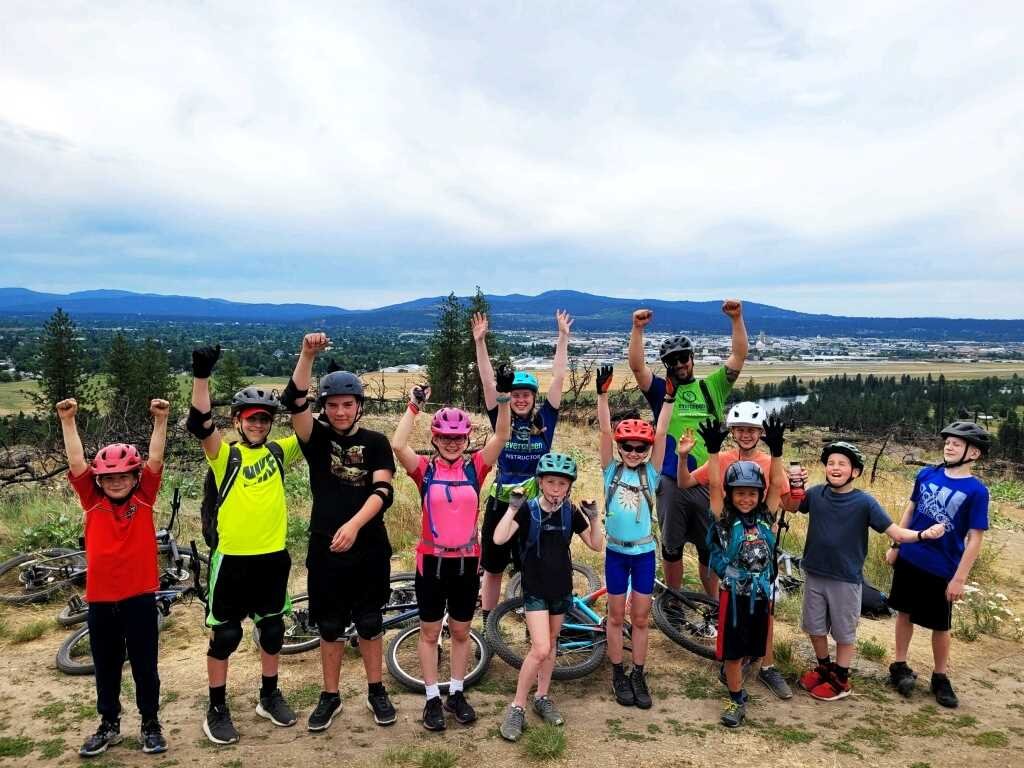 Evergreen East Dirt Camp mountain bikers smiling and cheering.