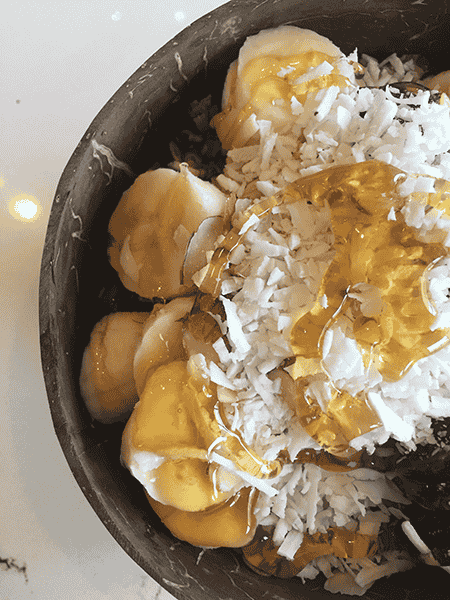 Photo of oatmeal with bananas, shredded coconut, and honey.