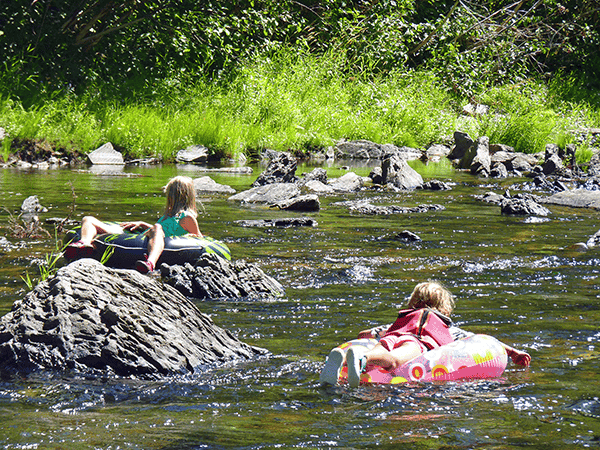 Photo of kids floating on tubes in a shallow part of the river.