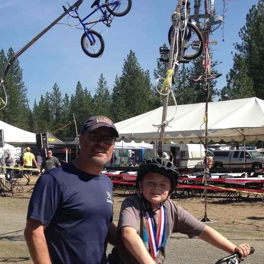 Father stands next to son on bicycle