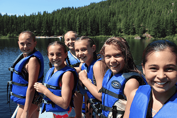 Photo of girls in life jackets on lake.