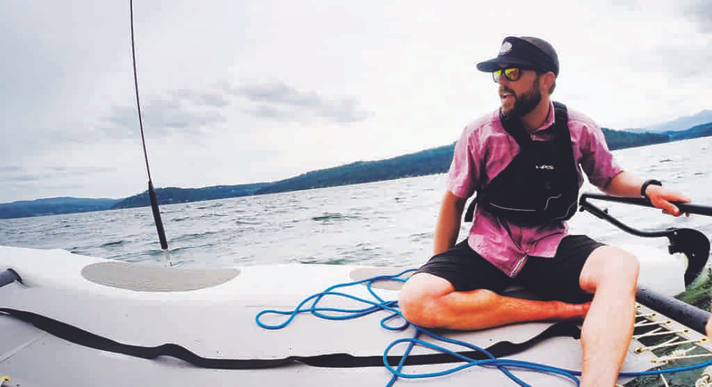 Photo of Jacob Rothrock reclining on a sailcraft on Lake Coeur d'Alene.