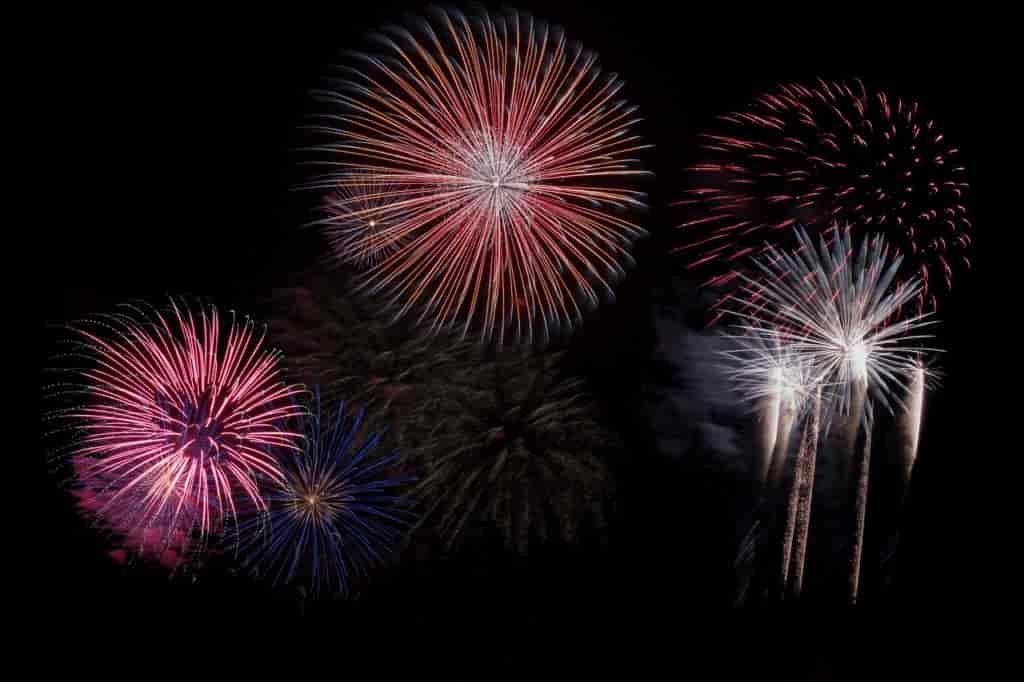 Red, white, and pink fireworks at night.