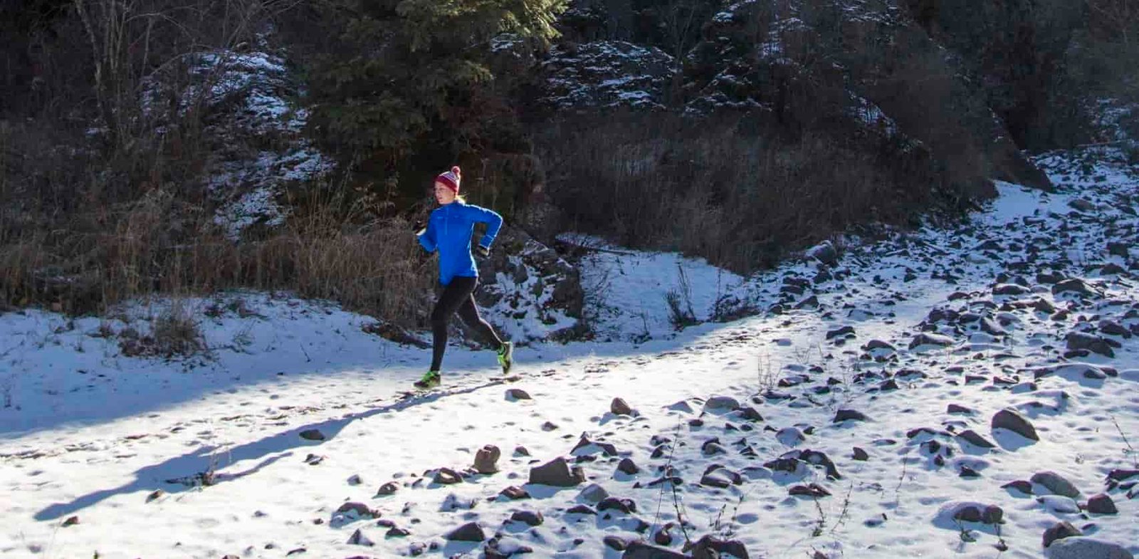 A person running though snowy rocks.