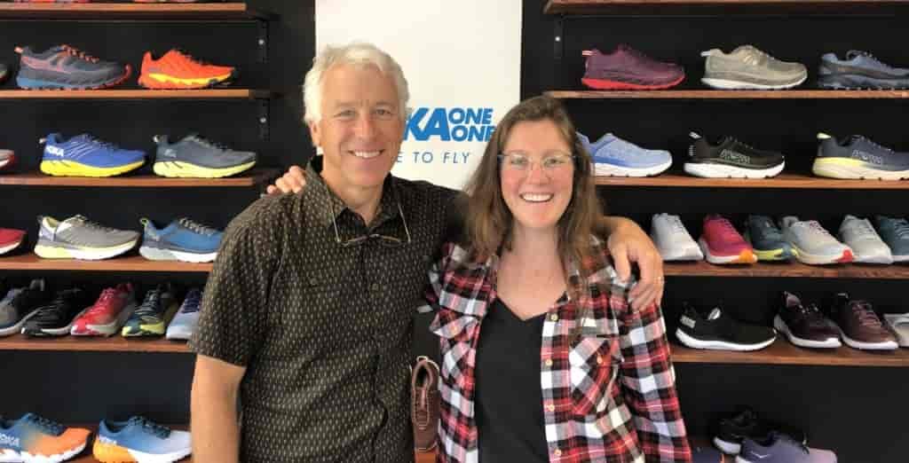 Two people posed in front of a shoe wall.