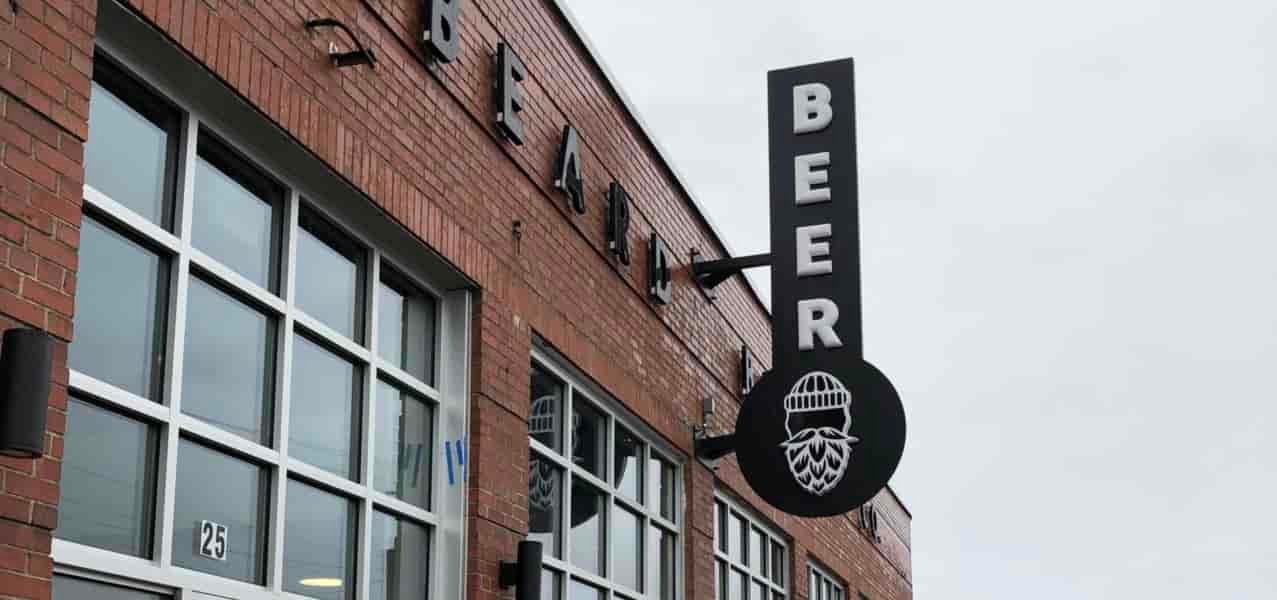A beer sign on the side of a brick building.
