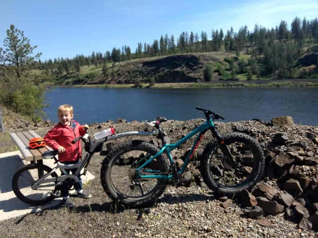 A little boy smiling with a bike.