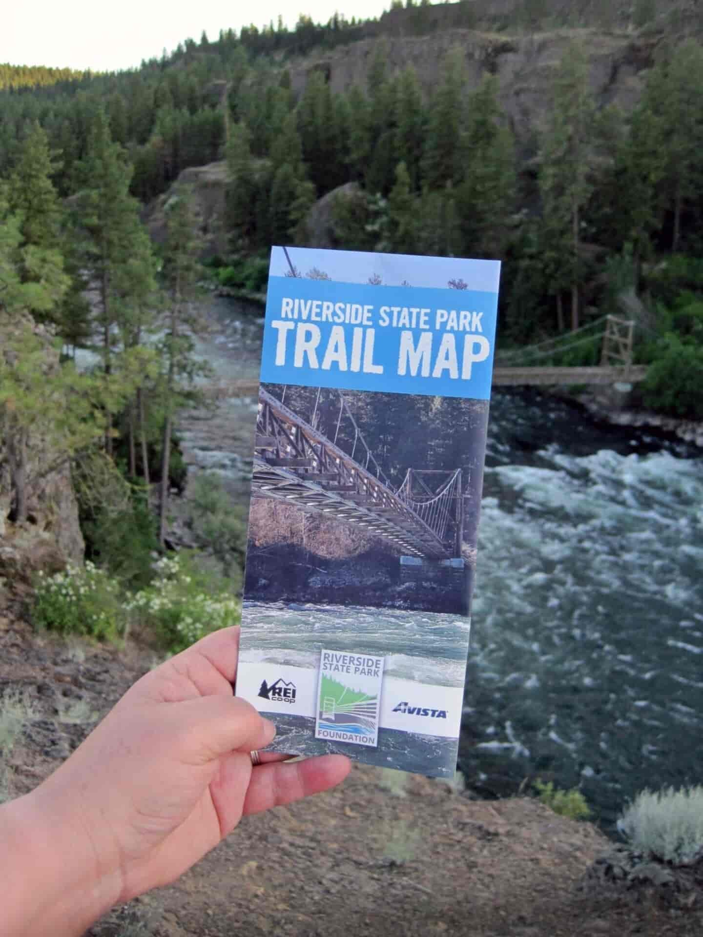 Person holding a brochure with a river in the background.