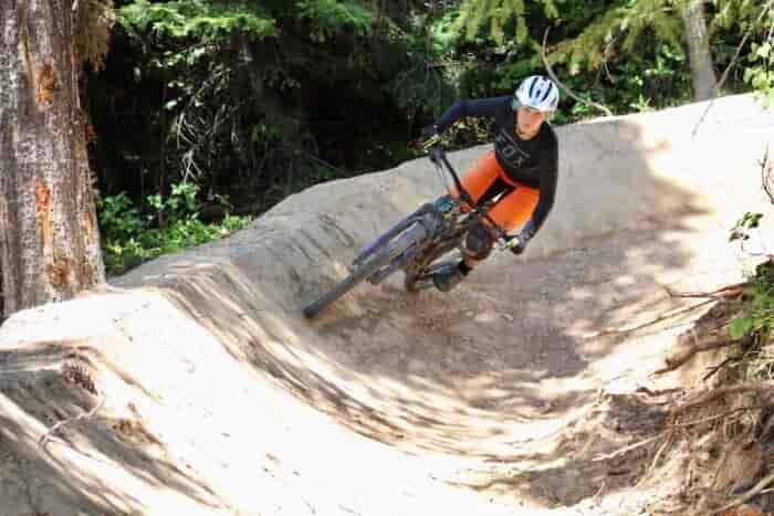 Person biking down a paved forest trail.