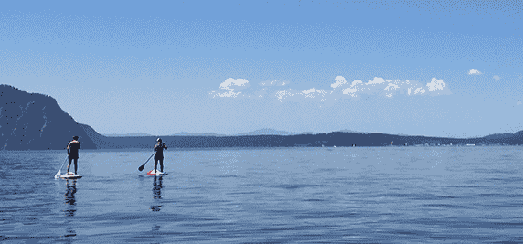 Two people stand-up paddling on the flat water of Lake Pend Oreille.