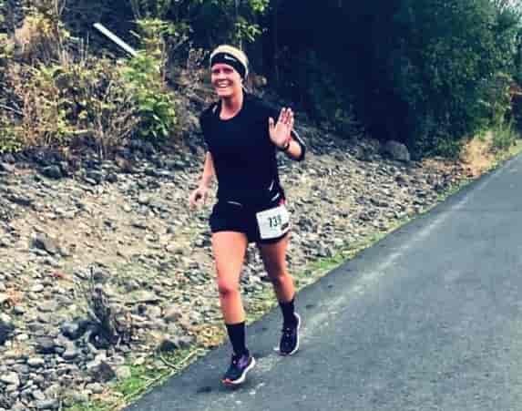 Crystal running in a race and waving and smiling at camera.