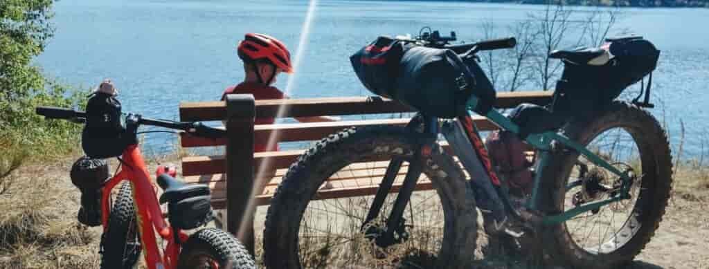 Child and parent taking a rest-break while biking on a trail above Fish Lake, with bikes resting against a bench.